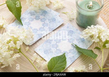 Pont avec cartes d'ange de divination maison sur la table en bois avec fleur d'hortensia pour la décoration. Maison à l'intérieur brûlant des bougies. Banque D'Images