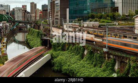 TOKYO, JAPON - AOÛT 09 2023 : image longue exposition (mouvement flou) de trains de métro et de train passant au-dessus de la rivière Kanda au pont Hijiribashi, Banque D'Images