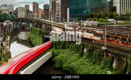 TOKYO, JAPON - AOÛT 09 2023 : image longue exposition (mouvement flou) de trains de métro et de train passant au-dessus de la rivière Kanda au pont Hijiribashi, Banque D'Images