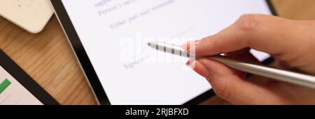 Une femme d'affaires appose sa signature sur son contrat sur sa tablette. Banque D'Images