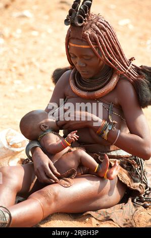 Himba allaitant son fils. Epupa, région de Kunene, Namibie. Banque D'Images