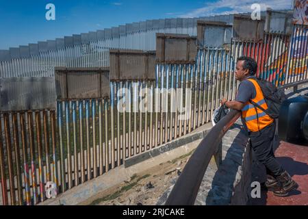 San Diego, États-Unis. 18 août 2023. Un travailleur mexicain regarde le mur frontalier construit aux États-Unis depuis la communauté balnéaire mexicaine de Playas de Tijuana le 18 août 2023. (Matthew Bowler/KPBS/Sipa USA) **AUCUNE VENTE À SAN DIEGO-SAN DIEGO OUT** crédit : SIPA USA/Alamy Live News Banque D'Images