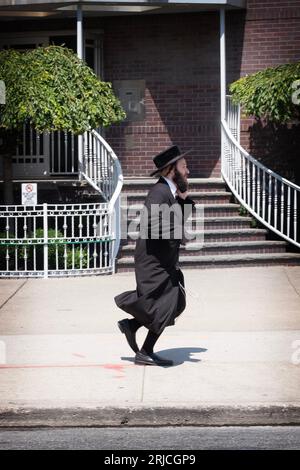 Un juif orthodoxe portant des bas noirs hauts court sur Wallabout Street à Williamsburg, Brooklyn, New York. Banque D'Images