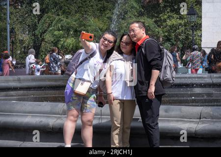 An Asian family, likely tourists, take a selfie in front of the fountain and the arch in Washington Square Park, Greenwich Village, New York City. Banque D'Images