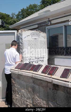 Un juif orthodoxe récite une prière personnelle dans un lieu Saint, le lieu de sépulture du Rabbi Ribnitz, Chaim Zanvil Abramowitz, à Monsey, NY, 2023. Banque D'Images