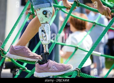 Brême, Allemagne. 22 août 2023. Une fille avec une prothèse de jambe grimpe sur un équipement de terrain de jeu à l'ouverture de la première aire de jeux inclusive à Brême, à la garderie de la communauté de l'église Dietrich Bonhoeffer. L'aire de jeux offre également un accès sans obstacle à divers équipements de jeux pour les enfants handicapés. Crédit : Focke Strangmann/dpa/Alamy Live News Banque D'Images