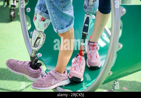 Brême, Allemagne. 22 août 2023. Les filles avec des jambes prothétiques se tiennent debout sur un équipement de terrain de jeu à l'ouverture de la première aire de jeux incluse à Brême, à la garderie de la congrégation de l'église Dietrich Bonhoeffer. L'aire de jeux offre également un accès sans obstacle à divers équipements de jeux pour les enfants handicapés. Crédit : Focke Strangmann/dpa/Alamy Live News Banque D'Images