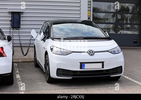 White Volkswagen VW ID.3 1st model charging battery at a wall charger of a car dealership. Salo, Finland. August 13, 2023. Banque D'Images