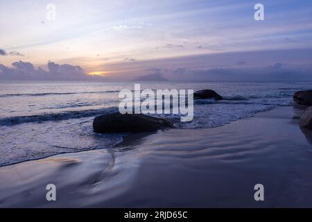 Paysage balnéaire avec sable humide et pierres côtières au coucher du soleil. Plage de beau Vallon, Seychelles Banque D'Images