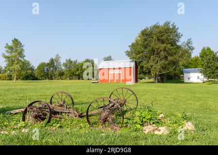 Vieille grange rouge et vieux matériel agricole rouillé dans l'Illinois rural. Banque D'Images