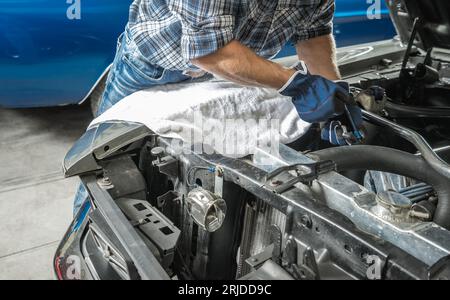 Mécanicien de voiture caucasien réparant le véhicule de moteur de combustion d'essence à l'intérieur de son atelier Banque D'Images