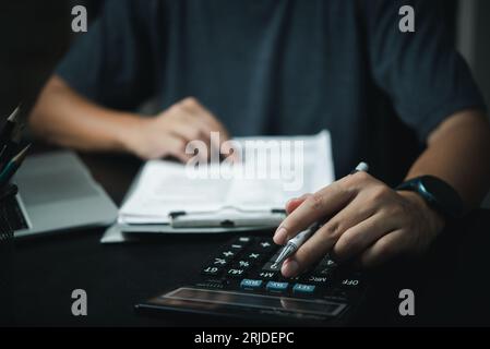 Homme d'affaires utilisant la calculatrice et les documents comptables au bureau avec ordinateur portable. Banque D'Images