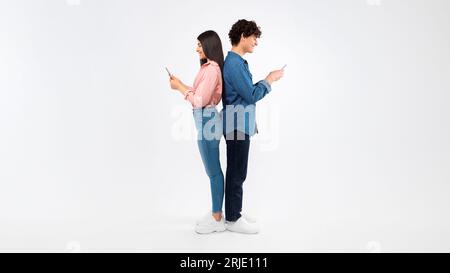 Heureux étudiants Jeune couple utilisant des téléphones cellulaires sur fond blanc Banque D'Images