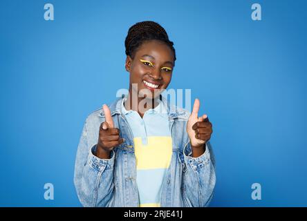 Positive jeune femme afro-américaine pointant vers la caméra et souriant Banque D'Images
