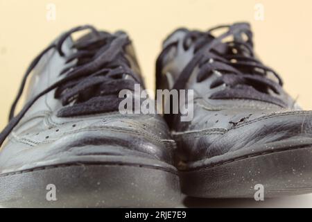 Une photo d'une paire de chaussures d'école noires avec des lacets défaits. Banque D'Images