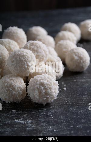 photo de nombreux bonbons au chocolat blanc à la noix de coco couchés sur la table, gros plan. dessert sucré, sucre, sur une planche de bois, espace vide Banque D'Images