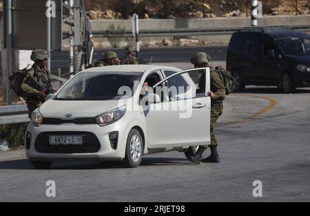 Hébron. 22 août 2023. Des soldats israéliens vérifient un véhicule à un point de contrôle près de la ville de Hébron en Cisjordanie, le 22 août 2023. Une femme israélienne a été tuée et un homme a été grièvement blessé lundi par un tireur palestinien dans une attaque en voiture en Cisjordanie occupée, selon l’armée israélienne. Crédit : Mamoun Wazwaz/Xinhua/Alamy Live News Banque D'Images