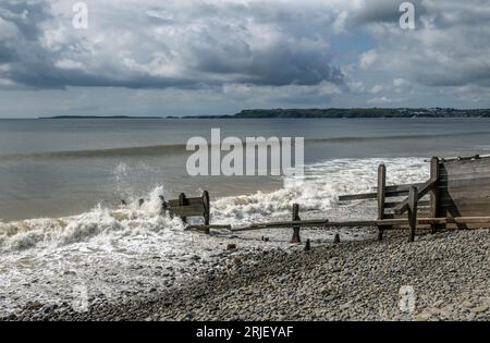 La côte du Pembrokeshire à Amroth avec une plage de galets et des brise-lames en bois lors d'une journée nuageuse ensoleillée en mai avec Saundersfoot derrière Banque D'Images