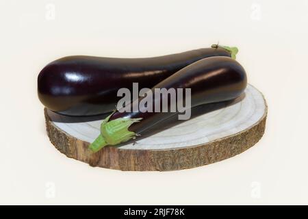 Deux aubergines mûres sur un support en bois, sur un fond clair Banque D'Images