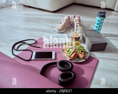 D'en haut de bruschetta de régime sain sur l'assiette et tasse de café entouré de divers équipements sportifs sur tapis de yoga Banque D'Images