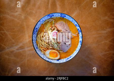 Vue de dessus bol de savoureuse soupe de ramen de porc japonais avec œufs et nouilles servis sur une surface en cuir dans le restaurant Banque D'Images