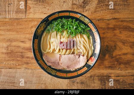 Vue de dessus de la délicieuse soupe de nouilles japonaises avec des morceaux de viande et des oignons verts hachés dans un bol sur une table en bois Banque D'Images
