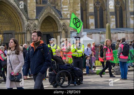 LONDRES - 22 avril 2023 : dialogue inclusif : les policiers métropolitains s'engagent avec un utilisateur de fauteuil roulant au milieu des manifestants XR lors de l'extinction Rebelli Banque D'Images