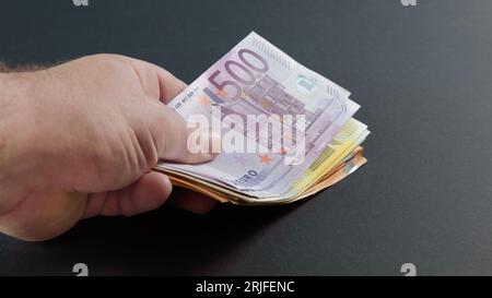 Paiement en espèces européen. la main détenant de gros billets en euros. gros plan sur fond noir Banque D'Images