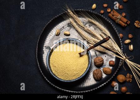 Couscous cru dans un bol en céramique noire sur une vue de dessus de table de fond noir rustique Banque D'Images