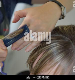 Un fragment de frange de coupe. Le processus d'une coupe de cheveux féminine. Gros plan Banque D'Images