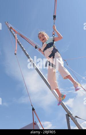 Fille sur attraction. Bande de caoutchouc sautant dans un parc d'attractions. Banque D'Images