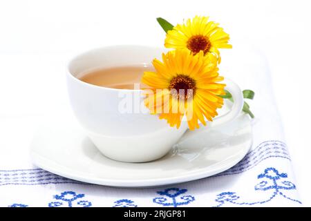 Tasse de thé et fleurs de calendula sur un torchon Banque D'Images