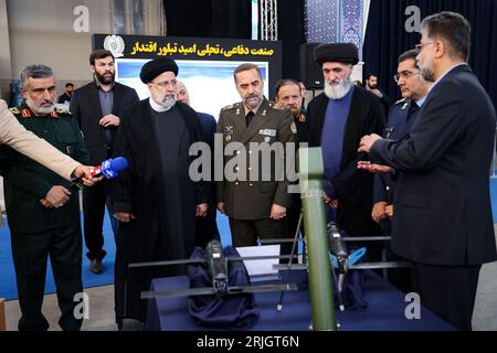 Téhéran, Iran. 23 août 2023. Le président iranien EBRAHIM RAISI (C) visitant une exposition au cours d'une cérémonie célébrant les réalisations de l'industrie de la défense du pays alors que son ministre de la Défense MOHAMMAD REZA GHARAEI ASHTIANI (L) et le chef de la division aérospatiale des Gardiens de la révolution, le général AMIR ALI HAJIZADEH (L), l'accompagnent. La cérémonie comprenait également le dévoilement d'un drone ressemblant au MQ-9 Reaper armé américain, affirmant que l'avion était capable de rester en vol pendant 24 heures et d'avoir la portée pour atteindre son ennemi juré Israël. La dernière version du Mohajer dr construit localement Banque D'Images