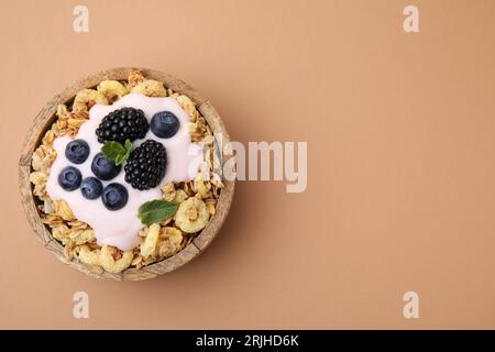 Granola savoureux, yaourt et baies fraîches dans un bol sur fond brun pâle, vue de dessus avec espace pour le texte. Petit déjeuner sain Banque D'Images