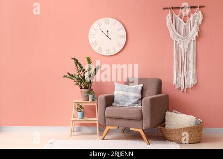 Élégant fauteuil brun et plante d'intérieur sur escabeau près du mur de couleur Banque D'Images