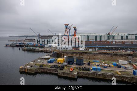 Kiel, Allemagne. 18 août 2023. Les nuages de pluie dérivent sur le chantier naval de ThyssenKrupp Marine Systems GmbH. La société a achevé une nouvelle salle ultramoderne pour la production de sous-marins. Crédit : Axel Heimken/dpa/Alamy Live News Banque D'Images