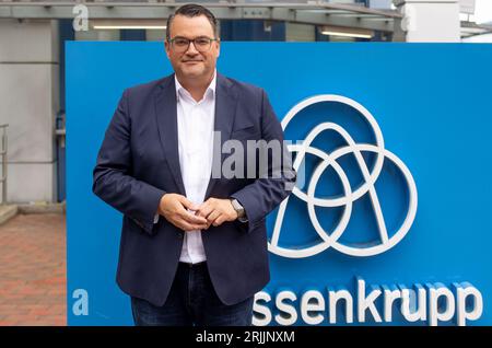 Kiel, Allemagne. 18 août 2023. Oliver Burkhard, PDG de ThyssenKrupp Marine Systems GmbH, se tient devant le logo de l'entreprise dans les locaux de l'usine. TKMS a achevé une nouvelle salle ultramoderne pour la production de sous-marins. (À dpa 'Construction de sous-marins à TKMS plus rapide et plus efficace dans le nouveau hall ') crédit : Axel Heimken/dpa/Alamy Live News Banque D'Images