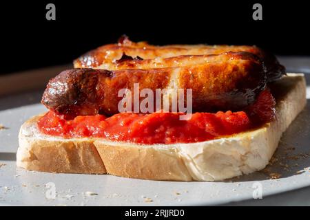 Tomates cerises hachées et saucisse de porc sur une tranche de pain blanc grillé. Sur une plaque grise Banque D'Images