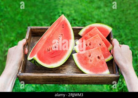 Femme tenant le plateau avec la pastèque fraichement tranchée. Focalisation sélective sur la pastèque. Dehors dans le jardin Banque D'Images