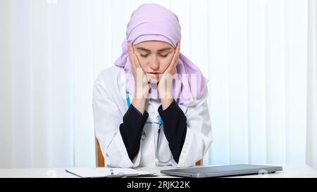 Femme musulmane en costume de médecin travaille avec l'expression fatiguée Banque D'Images