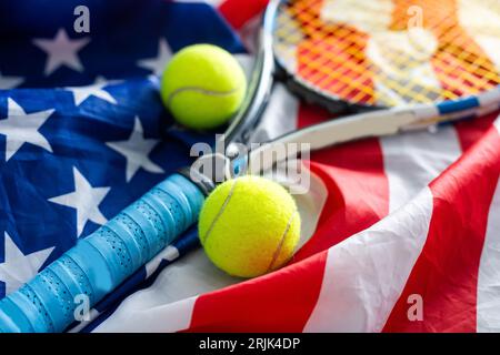 Compétition de tennis aux États-Unis. Composition sportive avec balles de tennis jaunes, raquette rouge et drapeau de l'Amérique sur fond vert. NOUS sommes ouverts. Pose à plat Banque D'Images