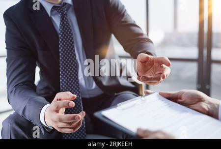 Deux hommes d'affaires sont assis sur des chaises dans le bureau pendant la conclusion d'un accord. Banque D'Images