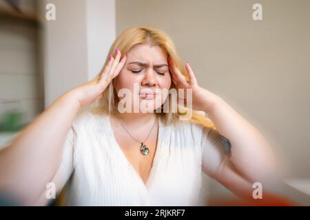 Femme en surpoids souffrant de migraine ou de maux de tête en raison du stress de longue durée ou de problèmes de santé Banque D'Images