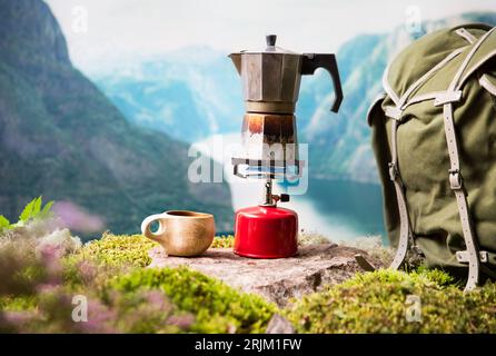 Cuisiner, faire du café ou du thé sur un brûleur à gaz de camping portable avec une bouteille de gaz rouge avec un fond de nature scandinave. Randonnée estivale, écotourisme, survie. Banque D'Images