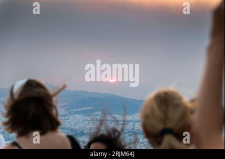 Le 22/08/2023 un feu de forêt a commencé sur les contreforts de la montagne Parnitha dans la banlieue ouest d'Athènes, Grèce. Alimentée par des vents violents, elle a rapidement grandi et brûlé des maisons et des commerces. Cette photo est de la colline de Lycabette, où les touristes et les habitants regardent le feu. Banque D'Images