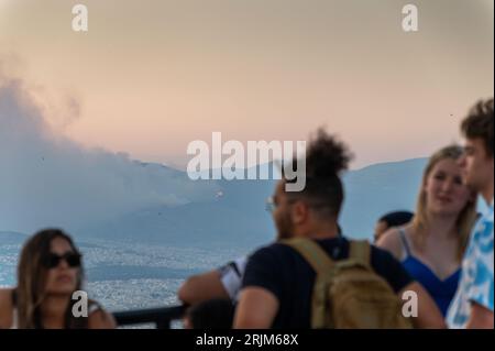 Le 22/08/2023 un feu de forêt a commencé sur les contreforts de la montagne Parnitha dans la banlieue ouest d'Athènes, Grèce. Alimentée par des vents violents, elle a rapidement grandi et brûlé des maisons et des commerces. Cette photo est de la colline de Lycabette, où les touristes et les habitants regardent le feu. Banque D'Images