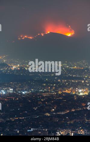 Le 22/08/2023 un feu de forêt a commencé sur les contreforts de la montagne Parnitha dans la banlieue ouest d'Athènes, Grèce. Alimentée par des vents violents, elle a rapidement grandi et brûlé des maisons et des commerces. Cette photo est de Lycabette colline dans le centre d'Athènes regardant vers la montagne. Banque D'Images