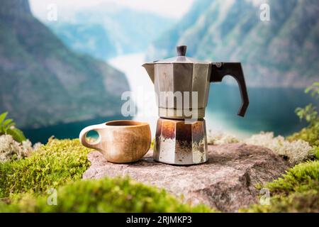 Café du matin avec une machine à café Moka et une tasse finlandaise traditionnelle en bois Kuksa dans un camp touristique avec en toile de fond un paysage scandinave Banque D'Images