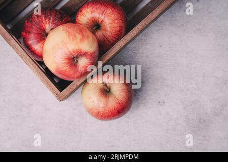 Les pommes rouges dans une caisse sur un plan de travail en béton ou une surface de travail avec un espace de copie pour un magazine Banque D'Images