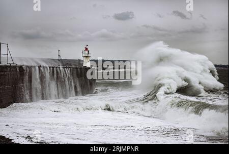 D'énormes vagues s'écrasent dans le port de Newlyn certaines atteignant aussi haut et au-dessus du phare qui se trouve sur le mur du port. Newlyn, Cornwall, Royaume-Uni Banque D'Images